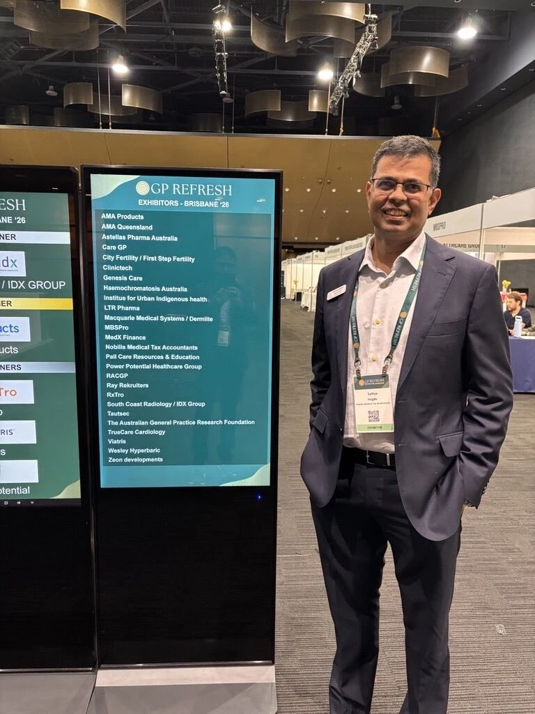 Sathya Hegde beside the conference information screens in Brisbane.